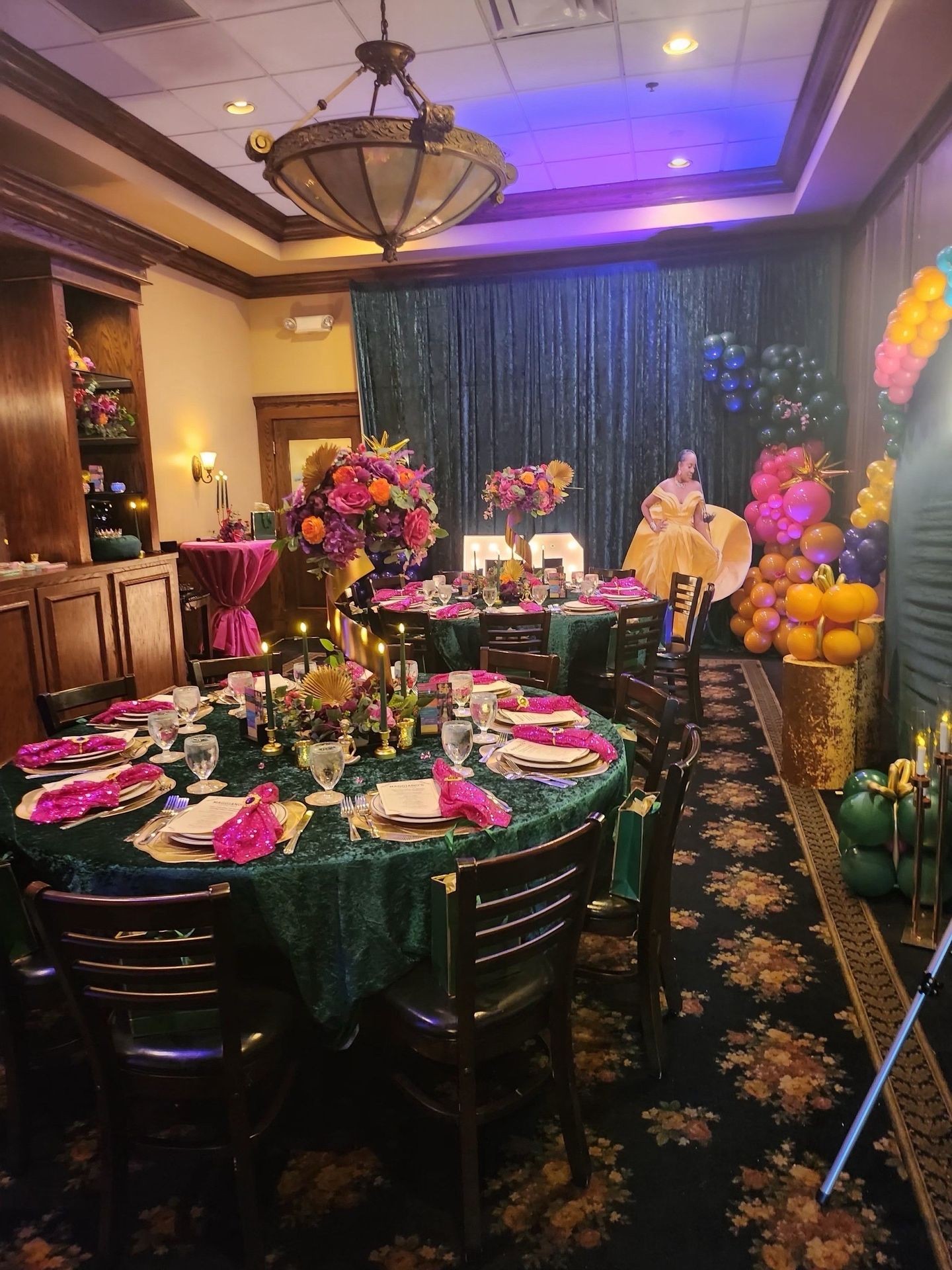 Elegant banquet hall with decorated tables, vibrant floral arrangements, and colorful balloons for a celebration.